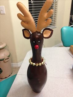 a brown vase with a deer head on it's face and some beads around its neck