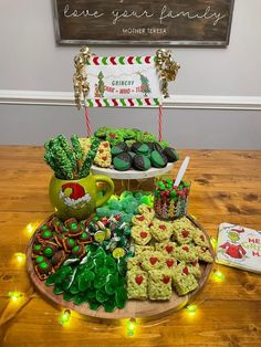 a platter filled with cookies and other treats on top of a wooden table next to a sign