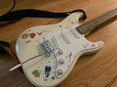 a white electric guitar with stickers on it's body sitting on the floor