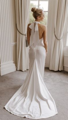 a woman in a white dress looking out the window with her back to the camera