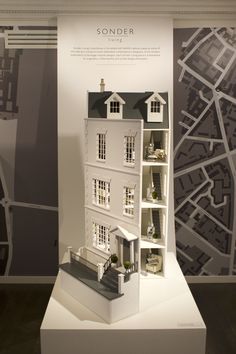 a model of a house on display in front of a wall with a map behind it