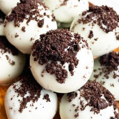 chocolate covered donuts with white frosting and sprinkles on a wooden platter