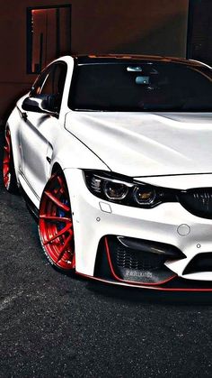 a white car with red rims parked in front of a building on instagram