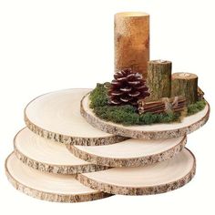 a stack of wooden slices with moss and pine cones on them, sitting next to a lit candle