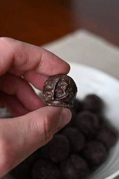 a person is holding a chocolate donut in front of a bowl of chocolate candies