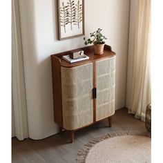 a wicker cabinet next to a window with a potted plant on top in front of it