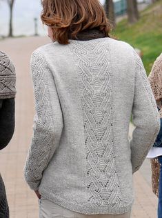 three women are walking down the sidewalk in knitted sweaters and jeans, one woman is holding an umbrella