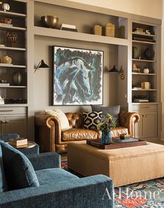 a living room filled with furniture and bookshelves next to a painting on the wall