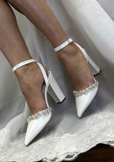 a woman wearing white high heels on top of a bed