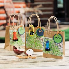 three paper bags with maps on them sitting on top of a wooden table next to nuts