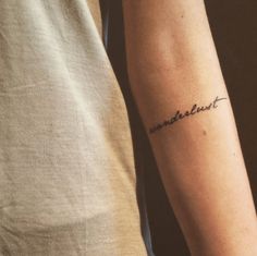 a man with a tattoo on his arm that says wanderment in cursive writing