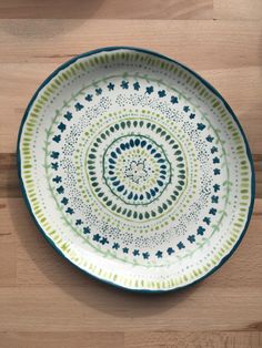 a green and white plate sitting on top of a wooden table