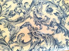 an intricately designed blue and white wallpaper with scrolls on it's sides