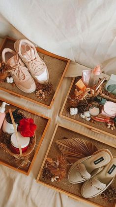 four pairs of shoes sitting on top of a bed next to candles and other items