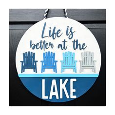 there is a sign that says life is better at the lake with chairs on it