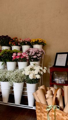 many different types of flowers are arranged in white vases on a shelf next to a basket