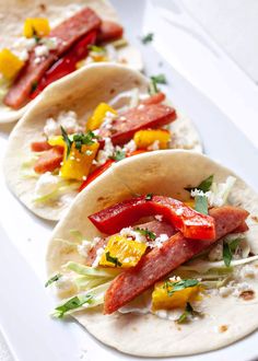 three tortillas on a white plate with peppers, cheese and other toppings