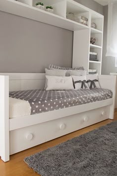 a white day bed sitting on top of a wooden floor next to a book shelf