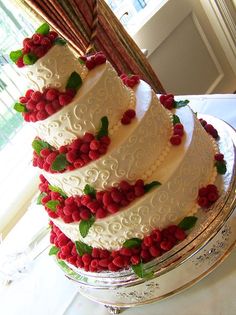 a triple layer cake with raspberries and leaves on top