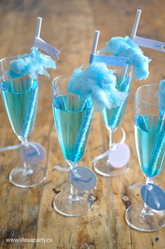 three glasses filled with blue liquid on top of a wooden table