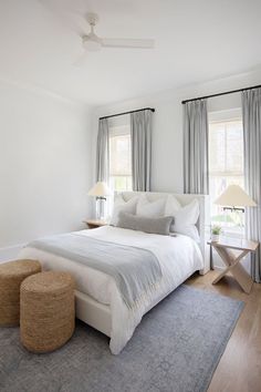 a white bed sitting next to two windows in a bedroom