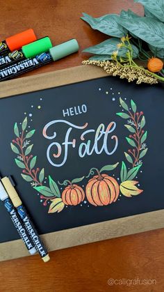 a chalkboard with the words hello fall written on it next to markers and crayons