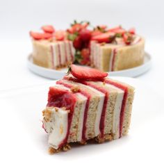 two slices of cheesecake with strawberries on top and one slice cut in half