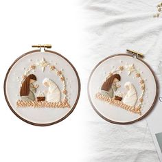 two cross stitch hoops with embroidered pictures of people in the middle one is holding a baby