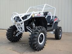 a white four - wheeler parked in front of a building with large tires on it