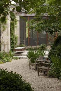 an outdoor garden with benches and plants around it, surrounded by greenery on either side of the building