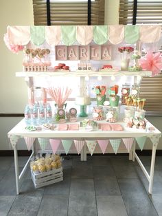 a dessert table with pink, green and white decorations on it's sides at a baby shower