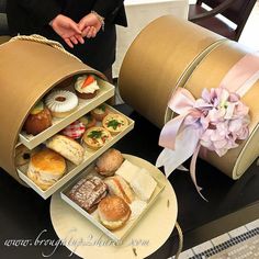 a woman standing next to two boxes with pastries in them on top of a table