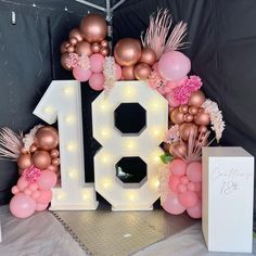 the number eighteen is surrounded by balloons and flowers in pink, gold and white colors