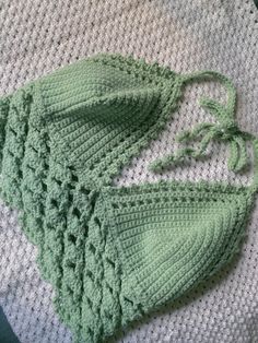 a crocheted green hat on top of a white blanket next to a pair of scissors