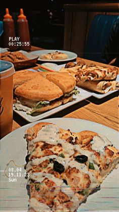 two slices of pizza sitting on top of plates next to cups and trays filled with food