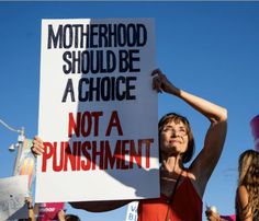 a woman holding a sign that says motherhood should be a choice not a punismment