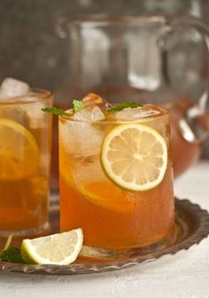 two glasses of iced tea with lemon and mint garnishes on a tray