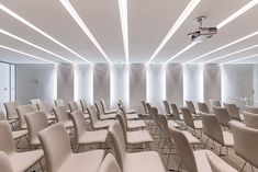 an empty conference room with rows of chairs and lights on the ceiling, all in white