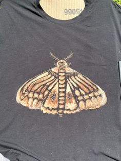 a close up of a butterfly on a t - shirt with grass in the background