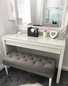 a white dressing table with a bench and mirror in the corner on top of it