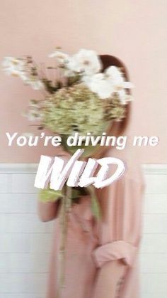 a woman holding a bouquet of flowers in front of her face with the words you're driving me wild