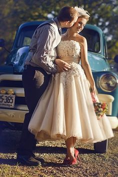 a bride and groom kissing in front of an old truck