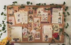 a cork board covered in lots of papers and flowers