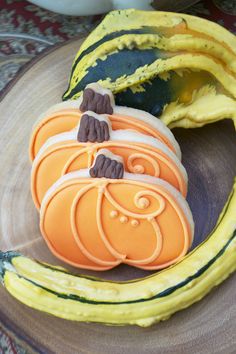 some cookies are sitting on a plate with pumpkins and bananas in the back ground