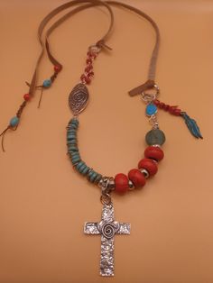 This Santa Fe Style Necklace is handmade by me.  I just love the Santa Fe style look!  It is casual and fun!  This  necklace has a lot of different elements to it.  It has four different sterling silver connectors, a sterling  silver artisan made bale ( the cross hangs on).  A large artisan made sterling silver cross, leather straps, coral turquoise beads (the four large  red beads), turquoise heishi beads ,  coral chips ( silver chain with coral chips and coral dangle on the side), and sterling silver connector with a turquoise stone.  Also, an African handmade glass bead ( the large light blue bead).  The necklace is  20 inches long including the cross pendant.  It is adjustable because it has a tie closure. Please visit my shop MyStylCraft if you'd like to see a  lot more Southwest styl Handmade Southwestern Cross Necklace, Southwestern Handmade Cross Necklace, Rustic Handmade Silver Necklaces, Rustic Silver Handmade Necklaces, Rustic Handmade Silver Necklace, Handmade Bohemian Cross Jewelry, Artsy Silver Jewelry For Festivals, Unique Handmade Cross Necklace, Santa Fe Style