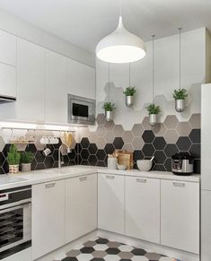 a kitchen with black and white tiles on the floor, potted plants hanging from the ceiling