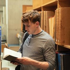 a young man reading a book in a library