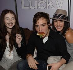 four people sitting on a couch eating food