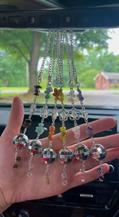 a person's hand is holding some beads in their car window hanging from the dash board