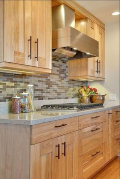 a kitchen with wooden cabinets and stainless steel range hood over the stove, along with wood flooring